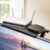 Estante repisa superior instalado sobre televisor, sosteniendo un router inalámbrico blanco y un dispositivo negro pequeño