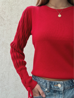 Sweater rojo de lana liso, con mangas anchas y detalle de transparencias. Puño con detalle de trenzado.