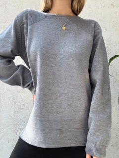 Sweater gris largo con detalles en los hombros y doble línea en la parte inferior.