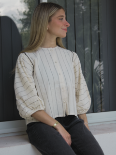 Modelo luciendo una blusa Zahora de rayas en tonos claros, con mangas abullonadas y botones frontales.