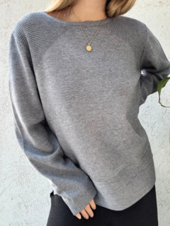 Sweater gris largo con detalles en los hombros y doble línea en la parte inferior.