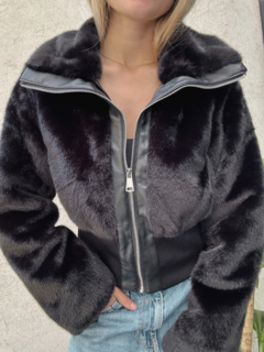 Campera Vendaval de piel sintética negra con cuello y cierre frontal, combinada con una prenda de color gris