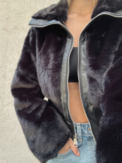 Campera de piel sintética con cuello y cierre frontal. Detalle de frunce en la parte inferior.