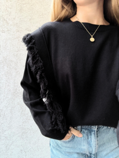 Sweater corte ancho y cuadrado, con detalles de flecos a los laterales y frunce en el cuello y mangas. Color Negro