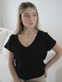 Mujer usando una remera negra de corte clásico con escote en V, con cabello largo y suelto.
