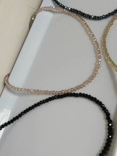 Collares de cristal en diferentes colores dispuestos sobre una superficie blanca.