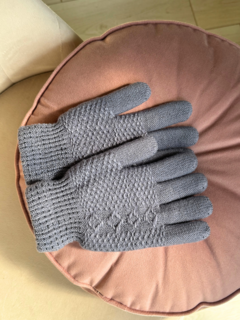 Guantes de lana grises sobre un cojín rosa claro