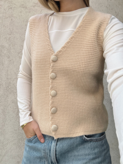Chaleco beige de lana corte medio, con cierre de botones forrados.