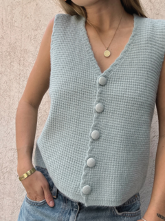 Chaleco Cumbre de color verde claro con botones en la parte delantera, combinado con jeans y joyería sencilla.