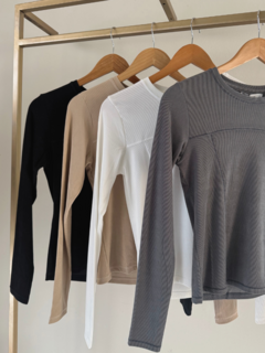 Remera Laurel de color beige, con un diseño de manga larga y textura acanalada, vista de varios colores en perchas
