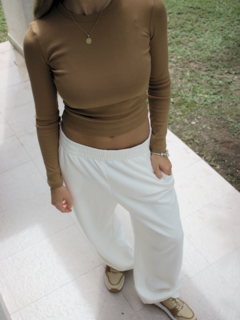 Pantalón Neblina blanco, combinado con un top marrón y calzado deportivo.