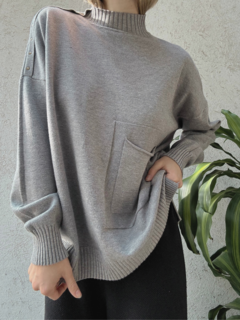 Sweater gris largo. Cuello alto y bolsillo frontal. Detalle de línea en los hombros y puños con frunce.