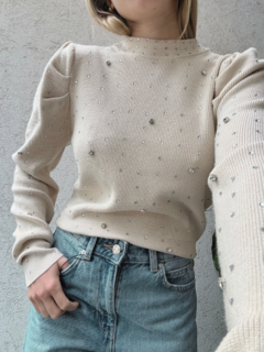 Suéter Cuarzo de color crema con detalles de perlas brillantes, combinado con jeans de tiro alto.
