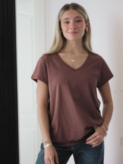 Modelo luciendo una remera de color marrón con escote en V y mangas cortas.