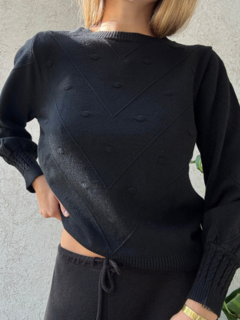 Sweater corte medio, con detalles en relieve y líneas formando triángulos invertidos que favorecen la silueta. Frunces en las mangas y parte inferior. Espalda lisa. Color negro