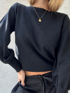Sweater corte medio, con detalles en relieve y líneas formando triángulos invertidos que favorecen la silueta. Frunces en las mangas y parte inferior. Espalda lisa. Color negro