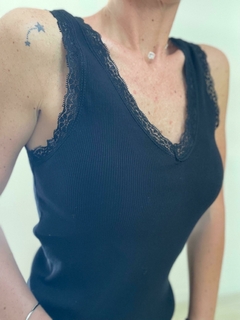 Remera negra de mujer con detalles de encaje en el escote y tirantes, ideal para uso diario.