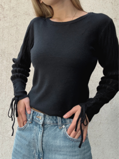 Sweater negro de lana liso, con mangas anchas y detalle de transparencias. Puño con detalle de trenzado.