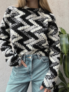 Sweater corto con cuello semi alto. Tonos blanco, negro y gris, con un diseño geométrico.