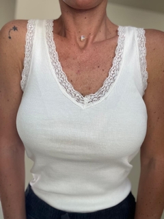 Remera blanca sin mangas con detalles de encaje en el escote, vista frontal.