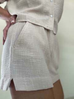 Shorts de color beige con textura, mostrando detalles de los bolsillos y el diseño en la parte lateral.