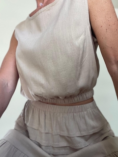 Top de lino en color beige, con cintura elástica y estilo relajado, parte de un conjunto de ropa.