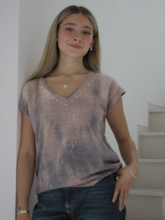 Modelo usando una remera de color tierra con detalles en el escote, de corte relajado y mangas cortas.