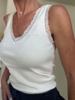 Remera blanca sin mangas con detalles de encaje en el escote