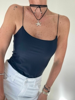 Body Topacio de color negro, con tirantes finos, combinado con un collar de estrella de mar y pantalones blancos.