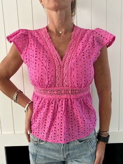 Blusa coco de color rosa con detalles de bordado y mangas cortas, combinada con jeans claros.