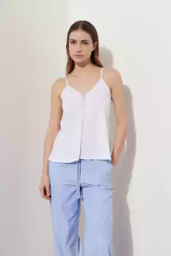 Modelo luciendo una remera blanca de tirantes con pantalones de rayas azules.