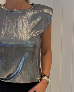 Remera hombreras JUANITA en tono plateado con brillo, vista frontal de la prenda sobre un fondo claro.