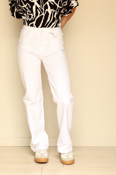 Pantalones de jean blancos, combinados con una blusa negra con estampado, mostrando un look moderno y casual.
