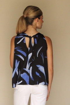 Blusa Sia de color negro con estampado azul, vista desde atrás, con un lazo en la parte superior.
