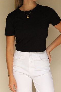 Modelo usando una remera corta negra de ZARA, combinada con pantalones blancos.