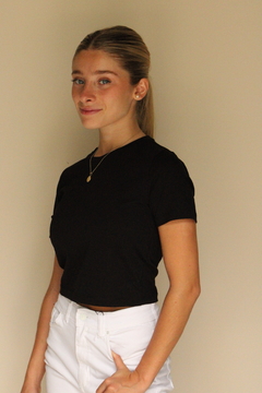 Modelo usando una remera corta negra de ZARA con pantalones blancos.