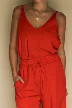 Musculosa Turmalina roja con escote en V y tirantes finos, combinada con pantalones de cintura elástica.