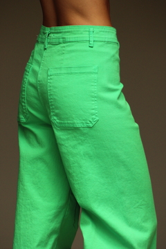 Pantalón verde brillante de corte amplio, visto desde el lado, con detalles de costura y bolsillos traseros.