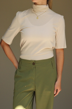 Pantalón Khalo en color verde olivo, con detalle de botonera y bolsillos, combinado con una blusa de manga corta color crema.