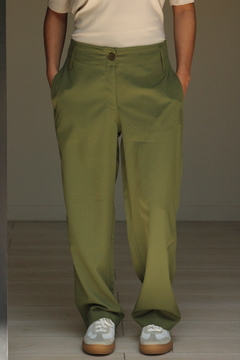 Pantalón Khalo de color verde, con bolsillos y un botón en la parte frontal, combinado con zapatillas claras.