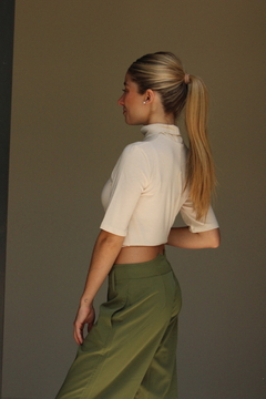 Mujer de perfil vistiendo un pantalón verde y una blusa corta beige, mostrando el diseño del pantalón Khalo.