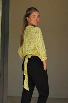 Blusa Solaris amarilla con estampado negro, vista posterior, combinada con pantalones negros.