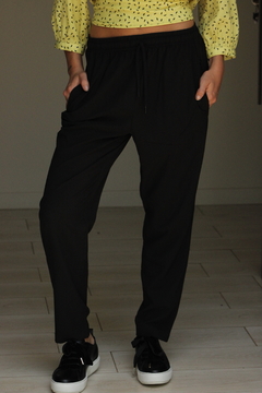 Pantalón Amalfi negro con cintura elástica y bolsillos, usado por una persona con blusa amarilla.