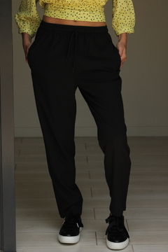 Pantalón Amalfi negro, con cintura elástica y bolsillos, combinado con una blusa amarilla con estampado.