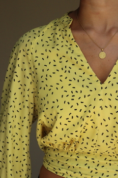Blusa Solaris amarilla con estampado negro, de manga larga y escote en V.