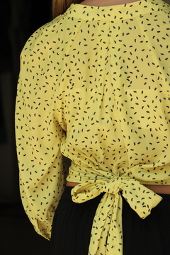 Blusa Solaris amarilla con estampado negro, vista posterior con un lazo en la cintura.