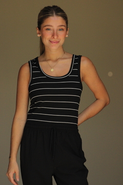 Modelo luciendo una musculosa Tuxi de rayas negras y blancas, con un fondo neutro.