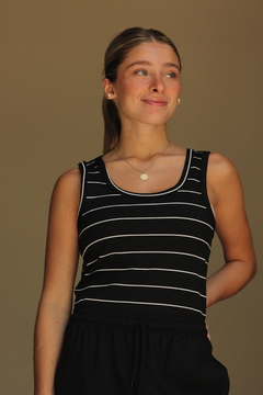 Musculosa Tuxi de rayas negras y blancas, modelo femenino posando con una sonrisa.