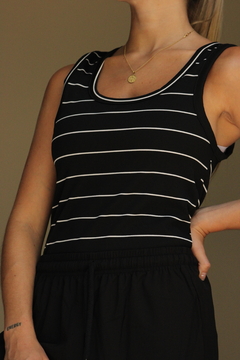 Musculosa Tuxi de color negro con rayas blancas, modelo ajustado y tirantes anchos, vista frontal.