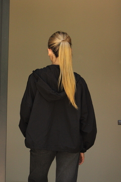 Mujer de espaldas vistiendo una campera negra, con el cabello rubio recogido en una coleta.